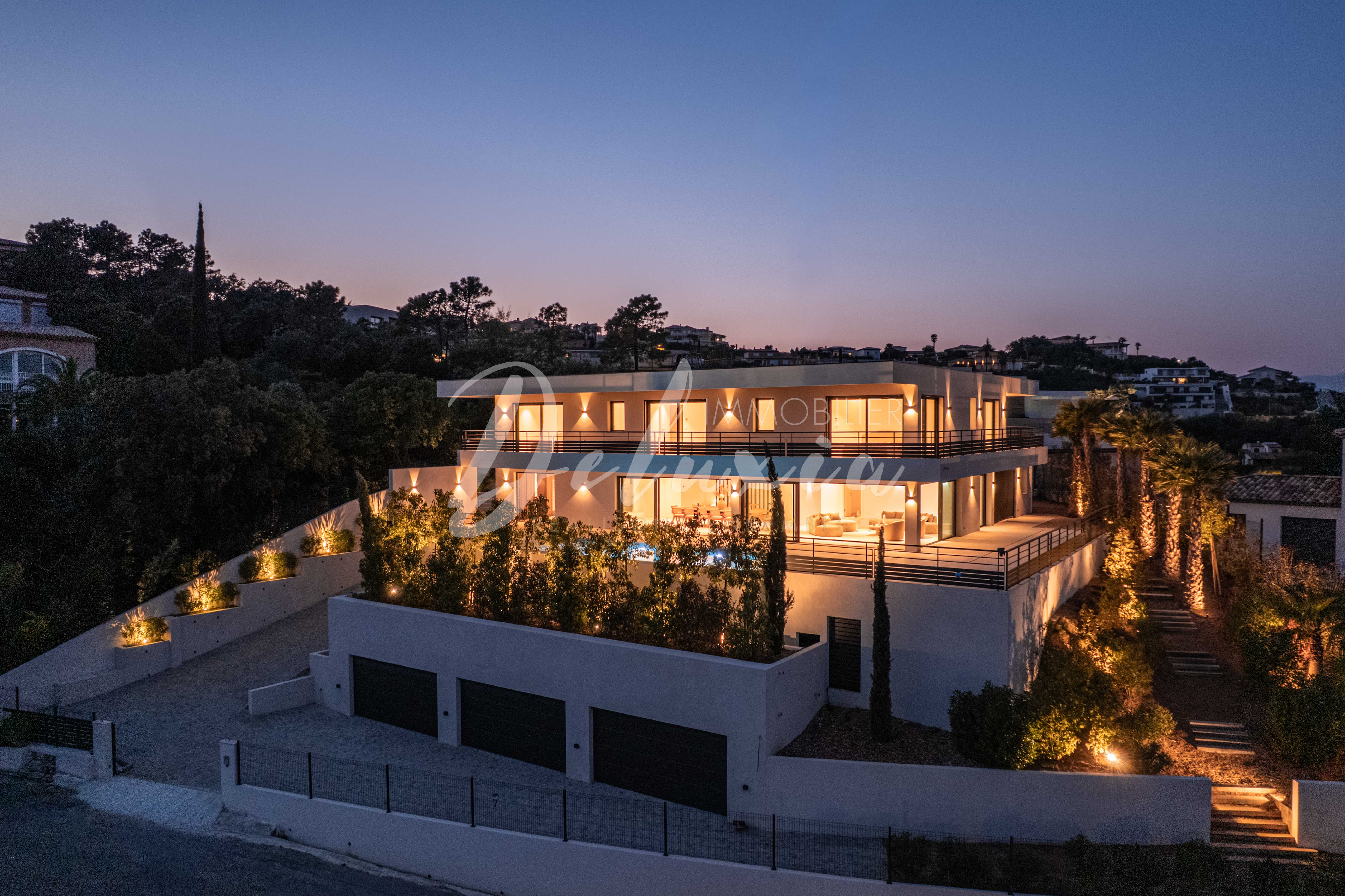 Villa contemporaine à vendre aux Issambres, architecture moderne avec éclairage extérieur et jardin paysager.